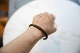 Antique African bronze striped cuff bracelet worn on a wrist.