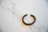 Antique bronze currency bracelet showing the open cuff design and textured patina.