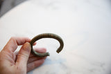 Profile view of the antique bronze cuff highlighting its C-shape and striped patina.