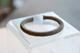 Angled view of an antique copper cuff's etched geometric texture and patina.