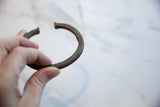 The antique African copper cuff bracelet held to show its curved form and texture.