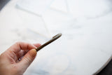 Detailed view of the faded diagonal etching and patina on an antique bronze bracelet.
