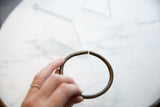 The scale and circular form of an antique African bronze bracelet held in hand.
