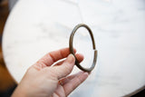 Antique bronze bracelet held to show its circular form and faded etched details.