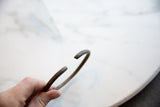 The open cuff of an antique African bronze bracelet with a dark, time-softened patina.