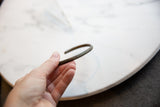 A hand holding the antique bronze bracelet to display its scale and aged patina.