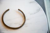 The simple, open form and aged patina of a vintage African bronze artifact.