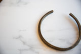 The open circular form and dark, aged patina of a vintage bronze artifact.