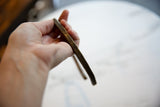In-hand view of the vintage bronze artifact showing its handmade geometric detailing.