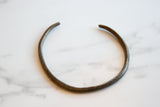 The curved shape and hand-etched geometric details of a vintage bronze artifact.