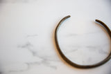 Side profile of the curved vintage African bronze artifact showing its aged texture.