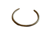 Vintage African bronze artifact with a C-shape and hand-etched geometric detailing.