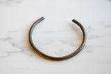 The open, circular shape and aged bronze patina of a handmade African artifact.