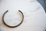 Vintage African bronze artifact displaying its smooth, aged patina and C-shaped form.