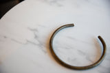 The curved shape and aged patina of the vintage African bronze artifact.