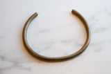 The aged bronze patina and smooth, curved surface of a vintage African artifact.
