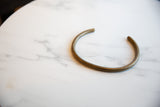 The open C-shape and smooth, aged patina of a vintage African bronze artifact.