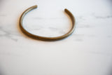 The complete arced shape and aged surface of the vintage bronze artifact.