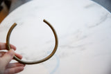 C-shaped vintage bronze artifact held to demonstrate its scale and aged patina.