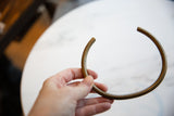 Vintage African bronze artifact held in hand to show its scale and curved shape.