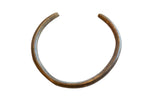 Vintage African bronze artifact in an open C-shape with a textured, aged patina.