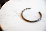 The curved form and dark, aged patina of a vintage bronze artifact.