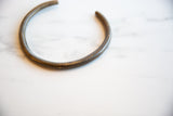 The open C-shape and time-worn patina of a vintage African bronze artifact.