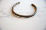 The simple, curved shape of a vintage African bronze artifact with a time-worn patina.