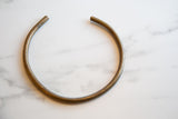 The open circular form and aged bronze patina of a collectible African artifact.