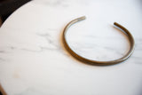 The simple curved form and warm patina of a handmade bronze artifact.