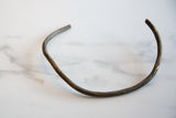 Vintage African bronze artifact showing its curved form and irregular hand-worked texture.