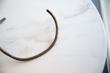 The rough, hand-worked surface and open end of the vintage bronze artifact.