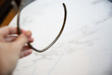 The curved shape and textured surface of a vintage bronze artifact held in hand.