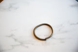 The time-worn patina and simple open-ring shape of the vintage African artifact.