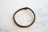 The dark, time-worn patina and simple open-ended shape of a vintage bronze artifact.