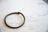 A detail showing the separated ends and aged patina of the bronze artifact.
