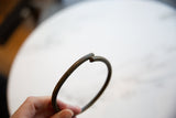 Close-up of the open gap and squared ends on the vintage bronze artifact.