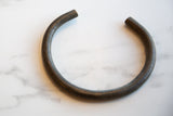 The solid, curved form and dark, textured patina of a bronze artifact.