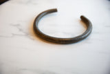 The open circular form and dark aged patina of a vintage bronze artifact.