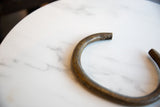 Close view of the handmade texture and aged patina on the African bronze artifact.