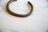 Hand-etched texture and warm patina along the curve of a vintage bronze artifact.