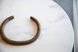 Detail of the handmade texture and worn patina on the open end of the vintage bronze artifact.