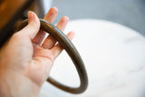 Hand holding the curved bronze artifact, detailing its aged patina and substantial thickness.