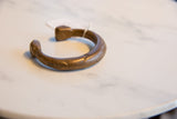 Angled profile of an antique African copper alloy cuff, showing its solid form and aged patina.