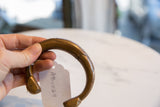 Antique African copper cuff bracelet held in hand, showing its attached handwritten tag.
