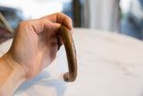 Antique African copper cuff held to show its substantial form and time-softened surface.