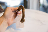 Antique African copper cuff bracelet held in hand, showing its item tag.