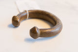 Angled view of an antique African bronze cuff showing hand-etched details and patina.