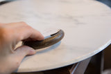 A hand holds the antique African bronze cuff, showing its scale and incised texture.
