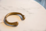 Close-up of the antique African bronze snake cuff bracelet's curved end, showing aged patina.